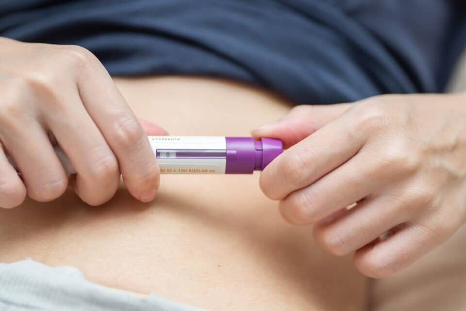 A woman adjust dosage of drug before injection at stomach or belly for increasing Ovarian Stimulation. IVF concept. Person in vitro fertilization treatment injection hormone for pregnancy